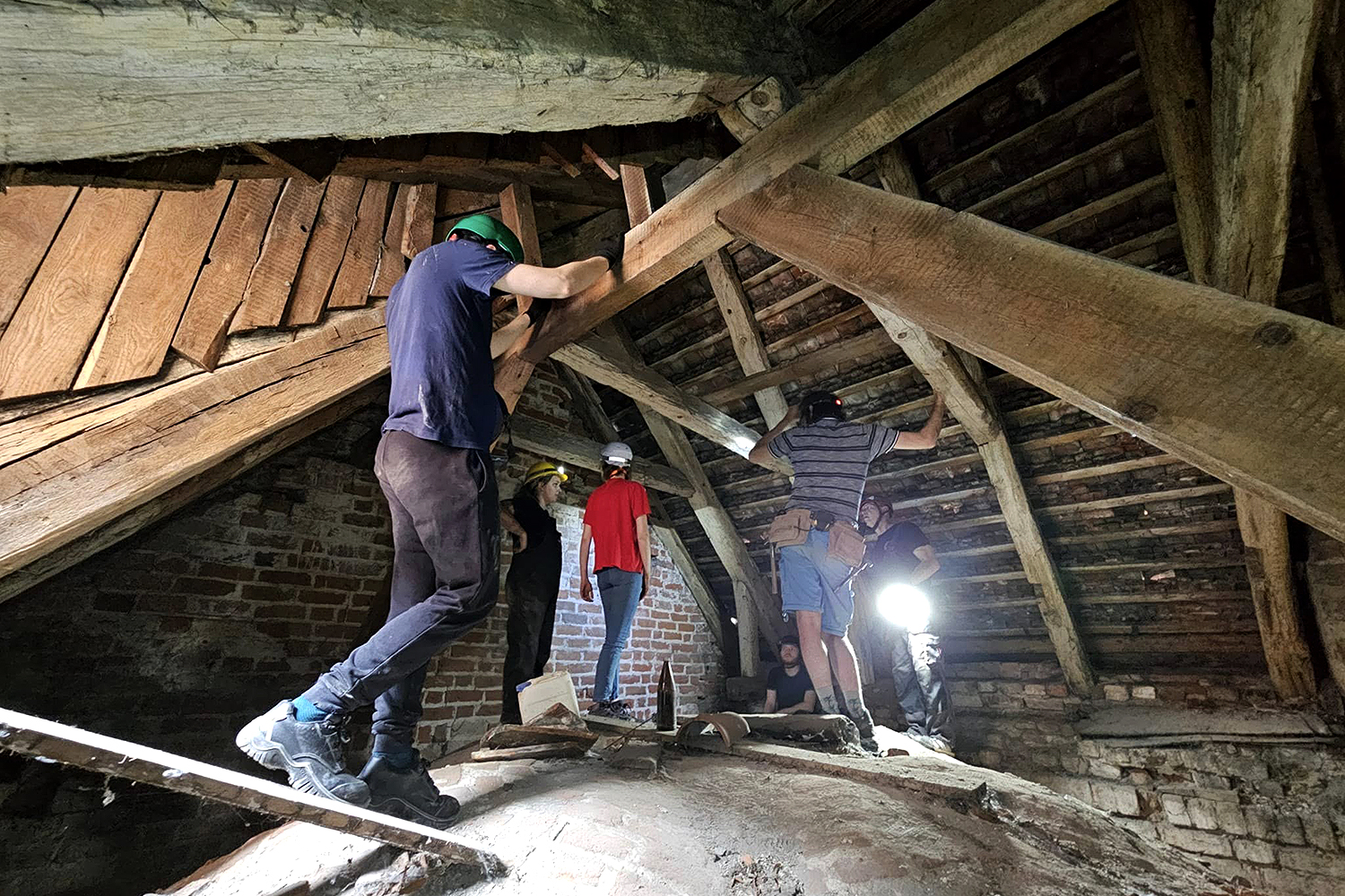 Studenci i studentki odbywający praktyki z badań architektonicznych w przestrzeni nadsklepienia w katedrze w Kamieniu Pomorskim.