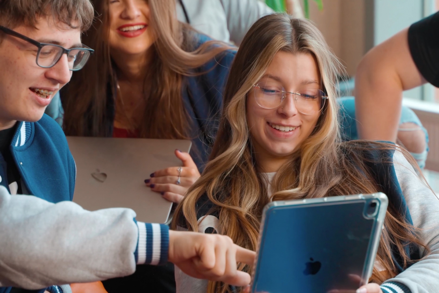 Student i studentka z uśmiechami na twarzach przeglądają coś w tablecie.